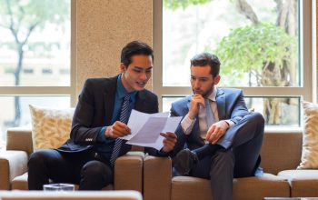 two-business-men-discussing-document-lounge_1262-3332